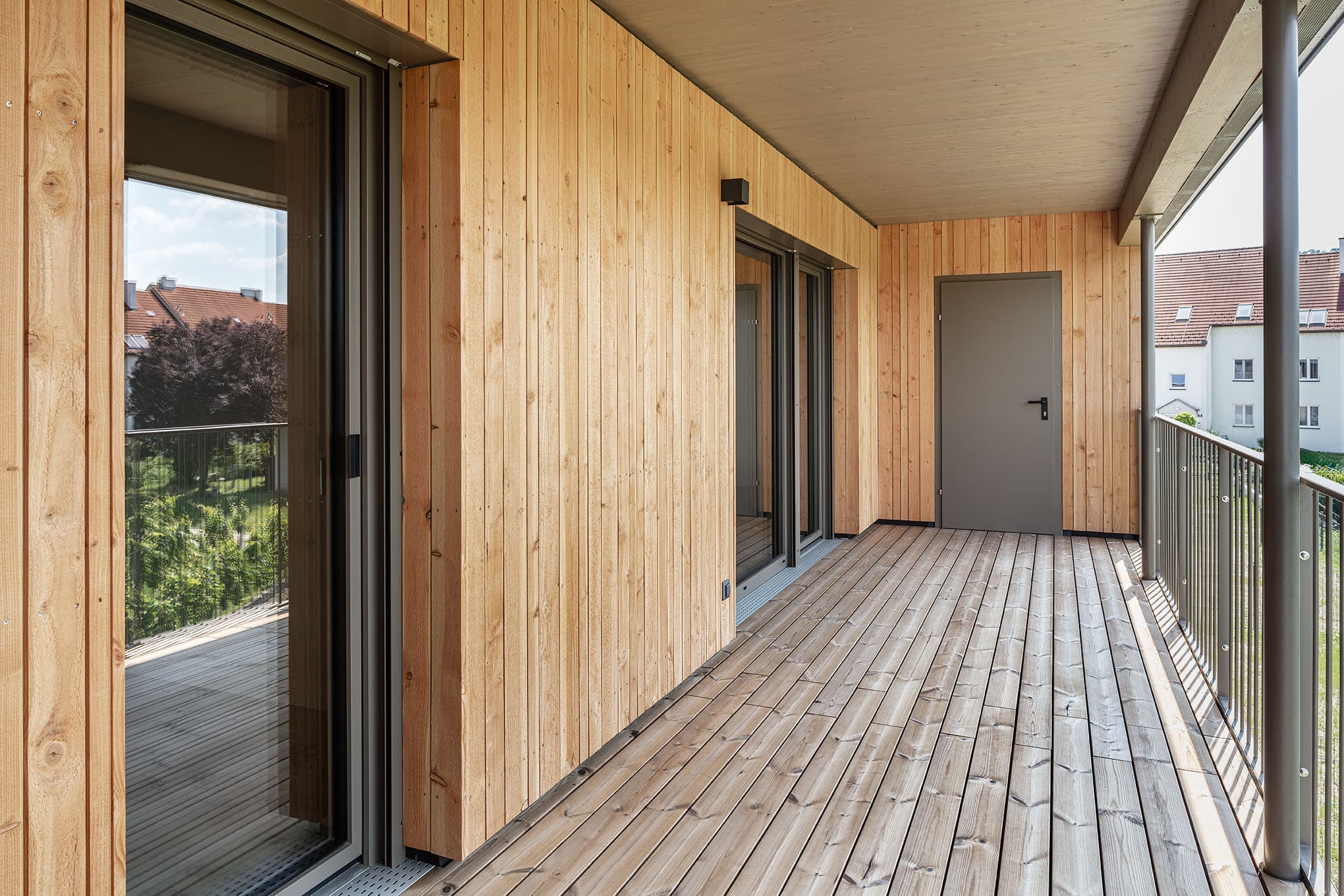 Loggia bei Massivholzhaus mit Holzfassade und Abstellraum.